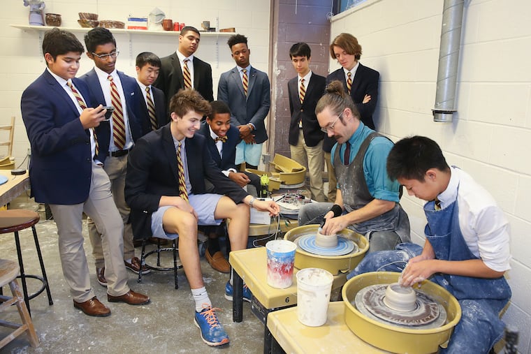 Haverford School students team who have won a Harvard soft robotics contest with a robotic glove that will help students to learn ceramics. Standing (l-r): Aditya Sardesai (junior), Yeshwin Sankuratri (junior), Toby Ma (junior), Troy Barnes (senior), Calvin Costner (senior), Safa Obuz (sophomore), Alexander Greer (junior)Sitting (l-r):Bram Schork (freshman), Josiah Somani (freshman) At wheel: Jacob Raeder (instructor)wearing the glove, left, drives the actuator finger of Daniel Chow (junior), right.