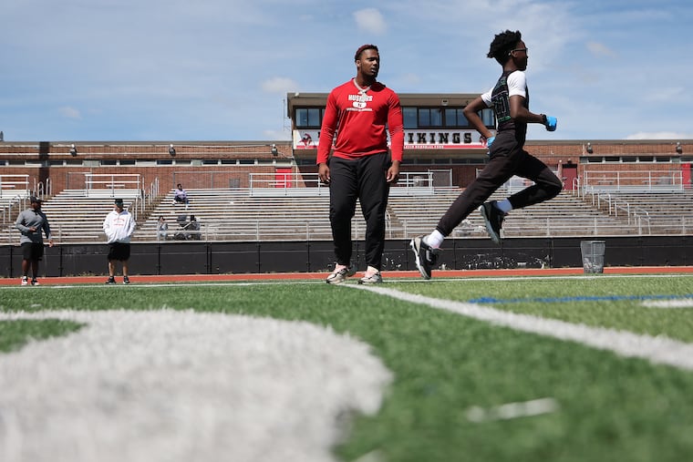 Elijah Jeudy, who is plays at Nebraska and went to Northeast, works with participants in a youth football camp at Northeast on May 25.